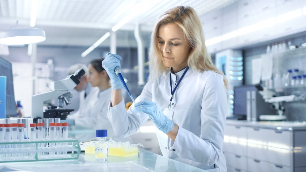 Female Research Scientist Uses Micropipette Filling Test Tubes in a Big Modern Laboratory.