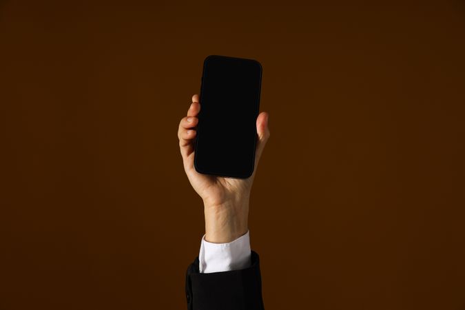 A man in a suit holds a smartphone