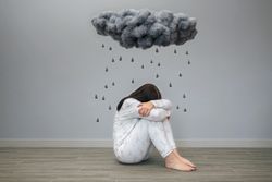Woman crying under a dark storm cloud and raindrops