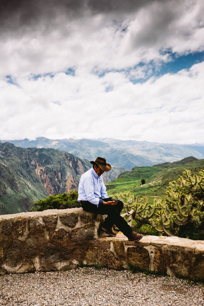 Side view of man checking phone in front of scenic view in Andes