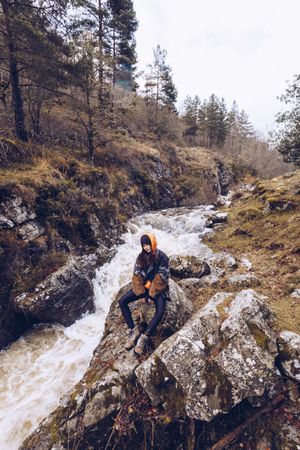 Woman gazing at fast mountain river in forest