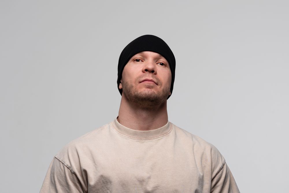 Man in beanie and beige t-shirt, serious expression