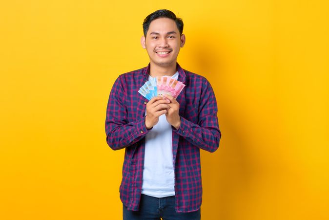 Happy Asian man holding up a fan of cash