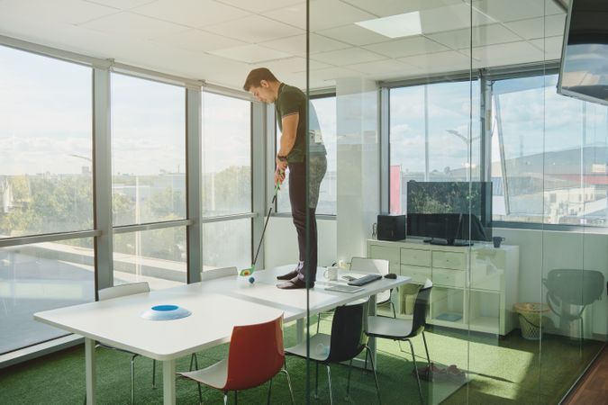 Man playing golf on table in office