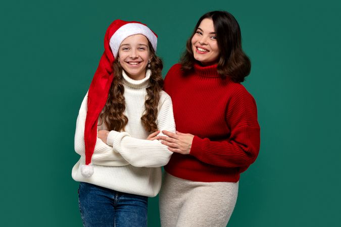 Mum, teenage daughter wearing red and white sweaters, arms linked