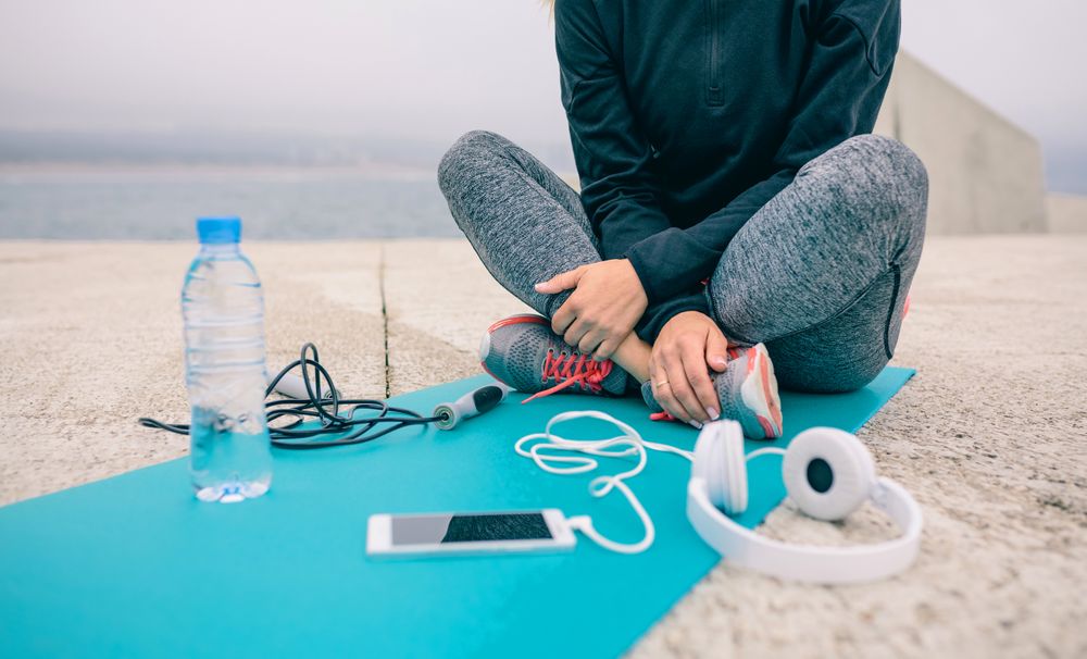 Low section of woman sitting with sport accessories