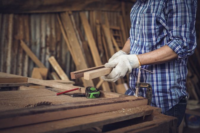 Hands of carpenter measuring a wooden panel in workshop