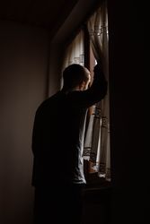 Male in casual wear standing by a window