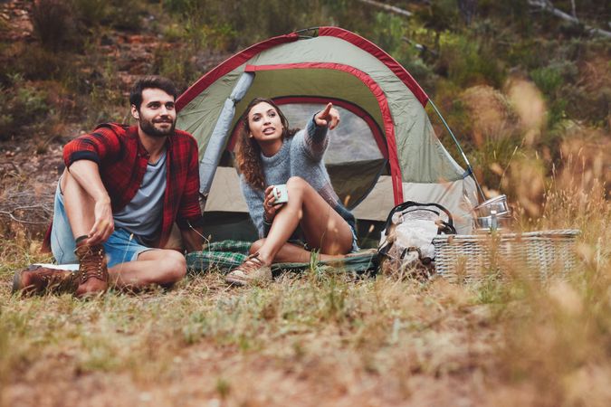 Young couple sitting outside a camping tent outdoors