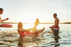 Multi-ethnic group of friends splashing in the lake at sunset