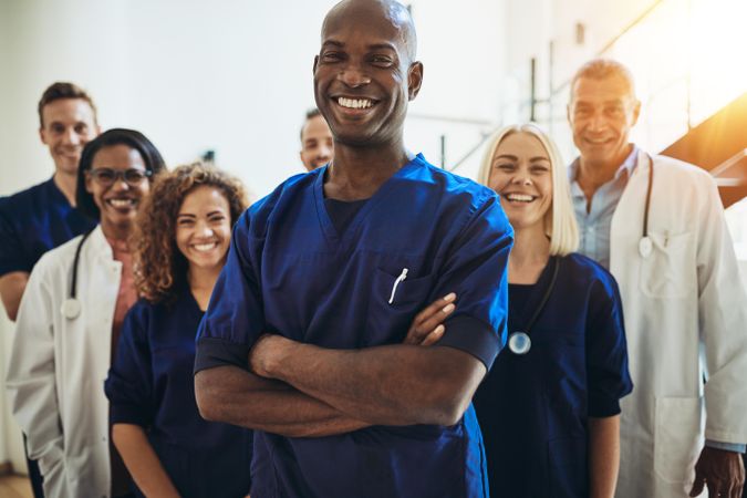 Smiling Black doctor with arms crossed pictured with medical team