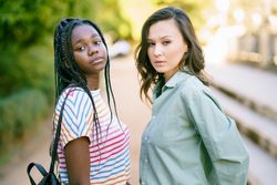 Two women friends in casual clothing posing in park walk way