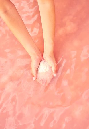 Female holding healing salt pile in pink water