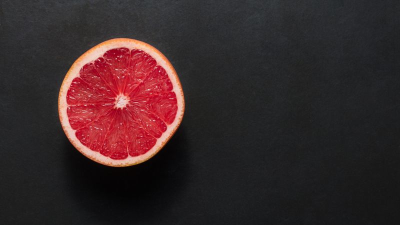 Top view of a half cut grapefruit placed on a dark background