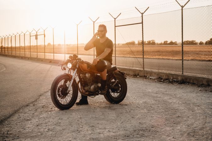 Man sitting on motorcycle and surfing mobile