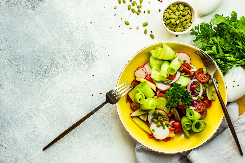 Raw salad with chopped vegetables served with nuts and garnish with copy space