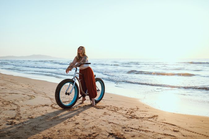 Joyful woman riding bicycle along peaceful beach