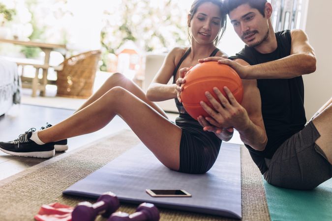 Healthy young couple doing exercises with a ball at home
