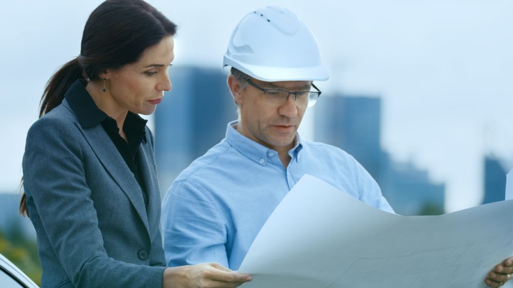 Chief Engineer Shows Project Drafts To Business Woman Investor.