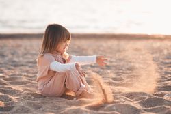 Girl in yellow outfit playing with sand at beach