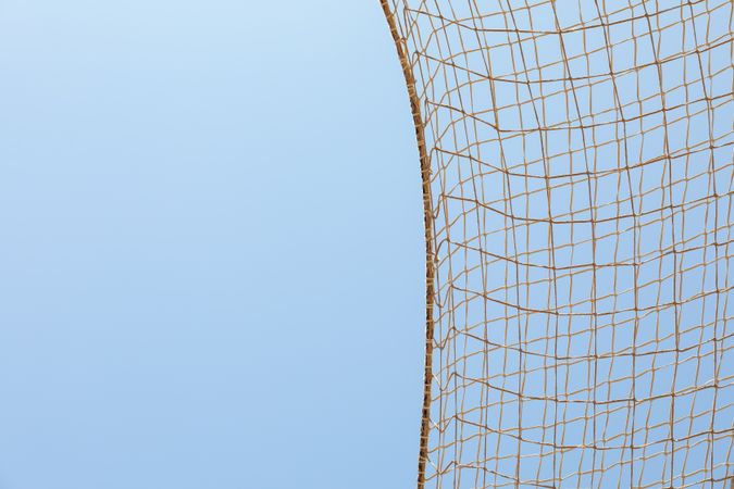 Football net against blue sky background, space for text