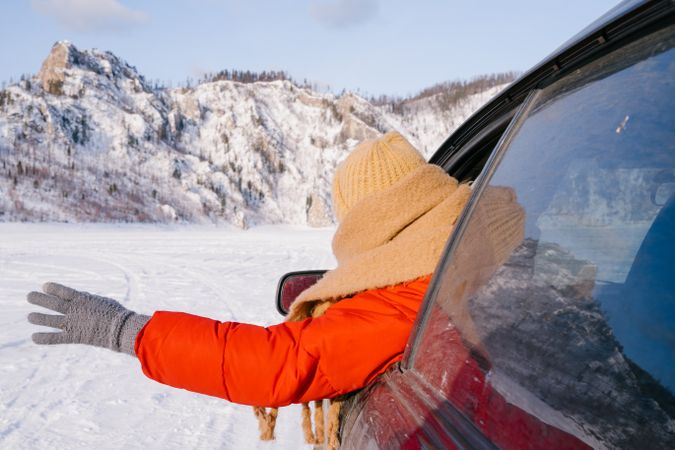 Woman leaning out car window on snowy valley