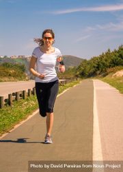 Woman in athletic gear jogging along road, vertical 4dOlD5