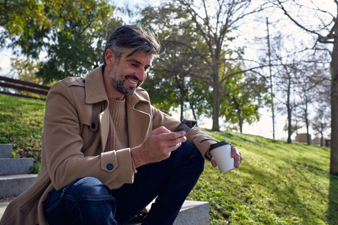Cheerful mature man surfing smartphone in park