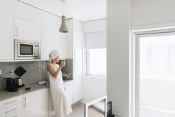 Pensive serene woman having refreshment with water in comfortable kitchen