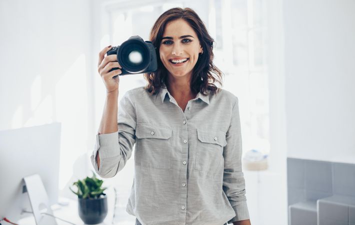 Freelance photographer holding digital camera in white studio