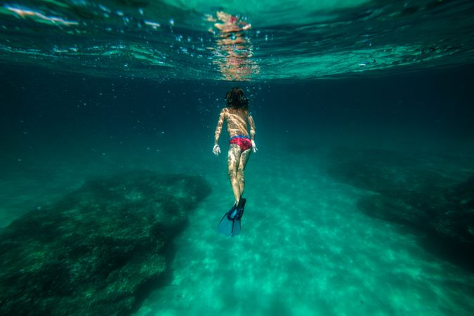 Boy in flippers and snorkeling mask swimming underwater
