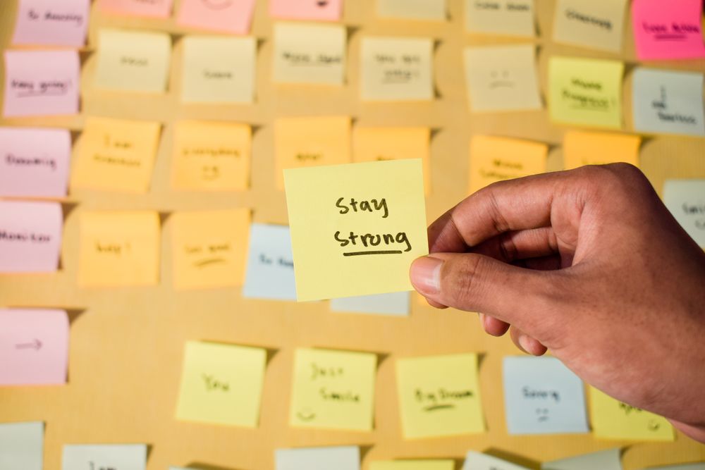 Hand hold sticky notes with words stay strong