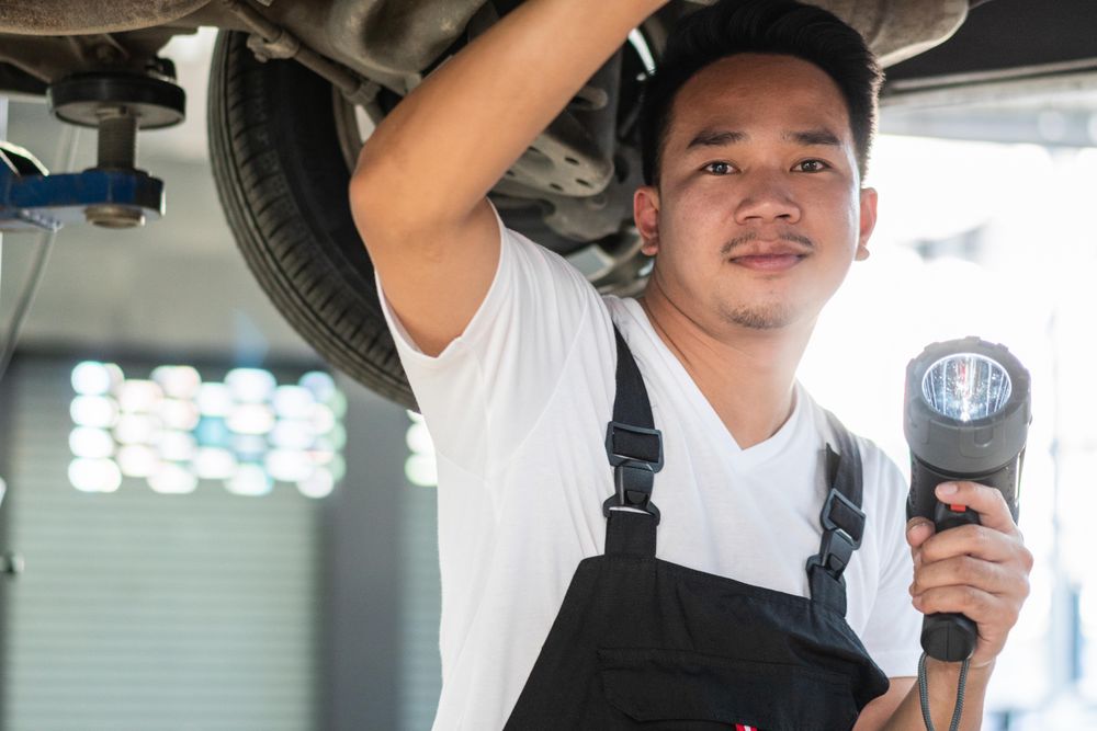 Male auto repairman working on undercarriage of vehicle