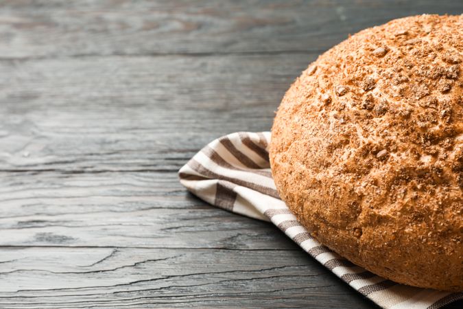 Bread on kitchen towel on wooden background, space for text and closeup