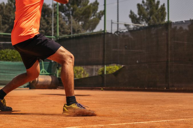 Man in sportswear playing tennis on a dirt tennis court