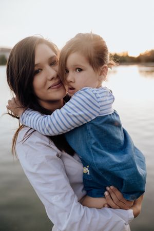 Mother and daughter standing near water