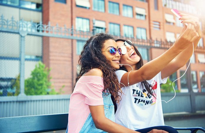 Young women wearing stylish sunglasses taking selfie together