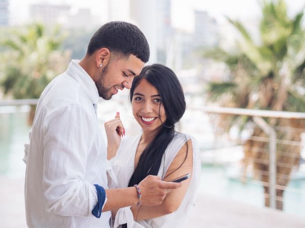 Man messaging on smartphone standing with woman