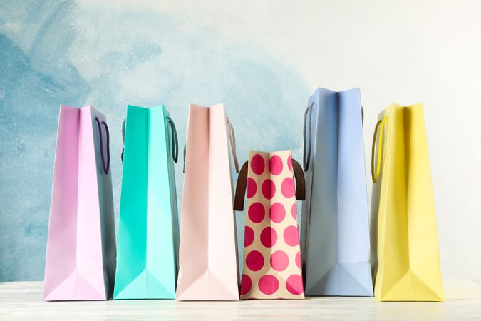Color bags on table against blue background, copy space