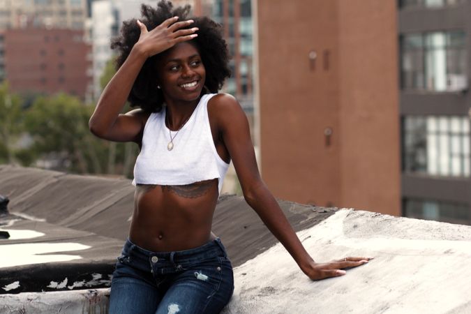 Woman in crop top standing on the roof smiling