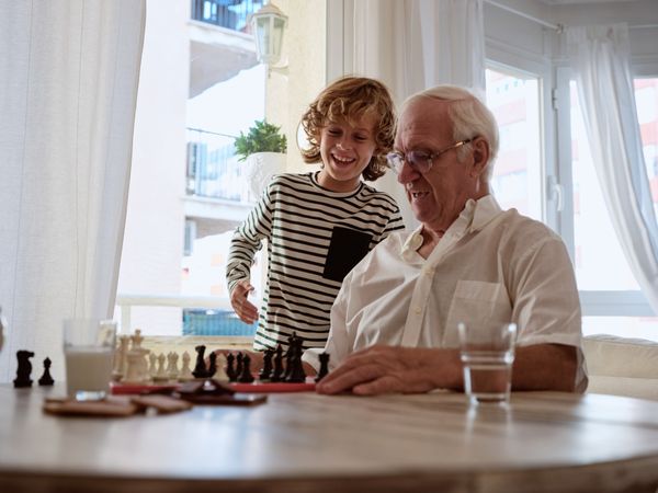 Cheerful boy near grandfather playing chess