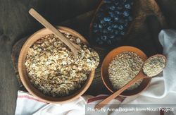 Wooden bowls of dry oats with blueberries on kitchen counter 56Go3j