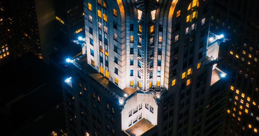 Aerial Shot of Night Scenery Over Manhattan's Lower East Side. Close Up Arc Shot of the Spire of the Chrysler Building with Lights Glowing from the Windows on the Roof
