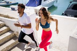 Man and woman working out on stairs near waterfront