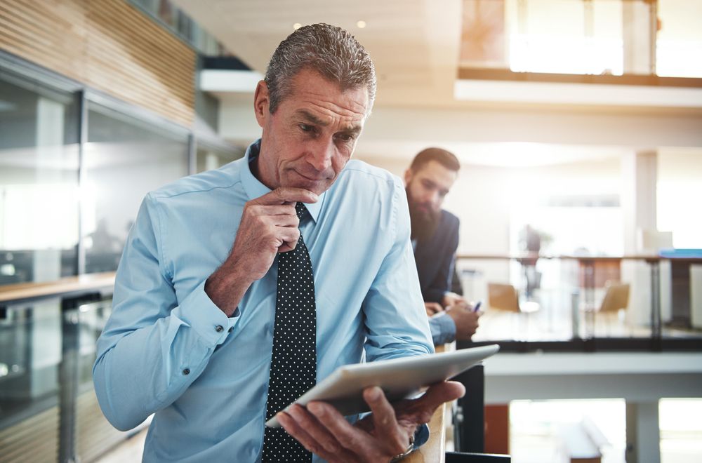 Man in business attire focused on his work using a  tablet