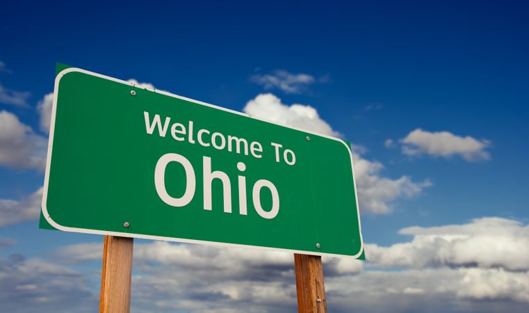 Welcome To Ohio Green Road Sign Over Blue Sky with Some Clouds.