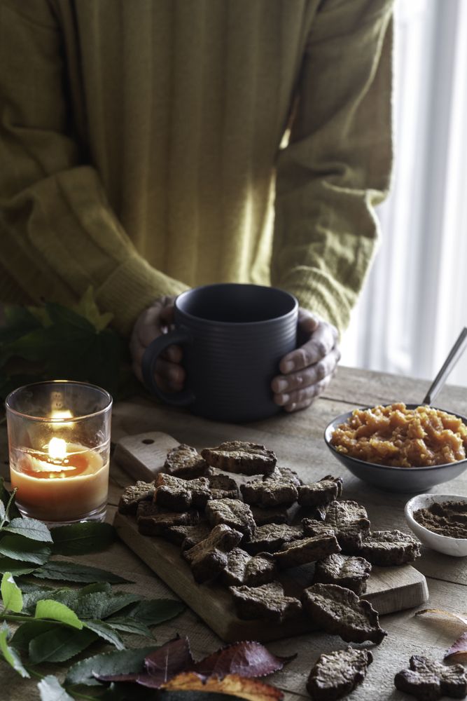 Crop person enjoying hot beverage and cookies