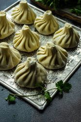 Trey of raw Georgian khinkali dumplings with cilantro