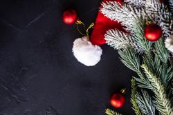 Pine branches with Santa decorations and red baubles on dark surface
