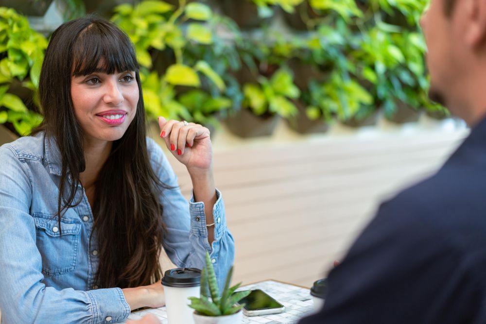 Smiling brunette woman with cup of coffee and talking with friend